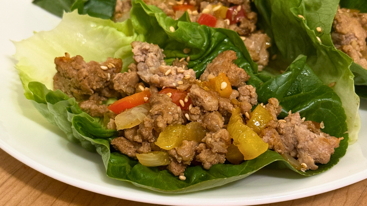 asian lettuce wraps on plate with sesame seeds on wooden table
