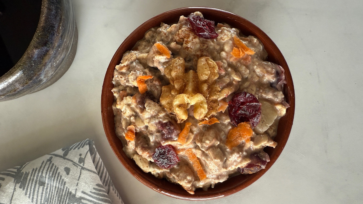 Bowl of carrot cake overnight oats with carrot shavings, walnuts, and cranberries.